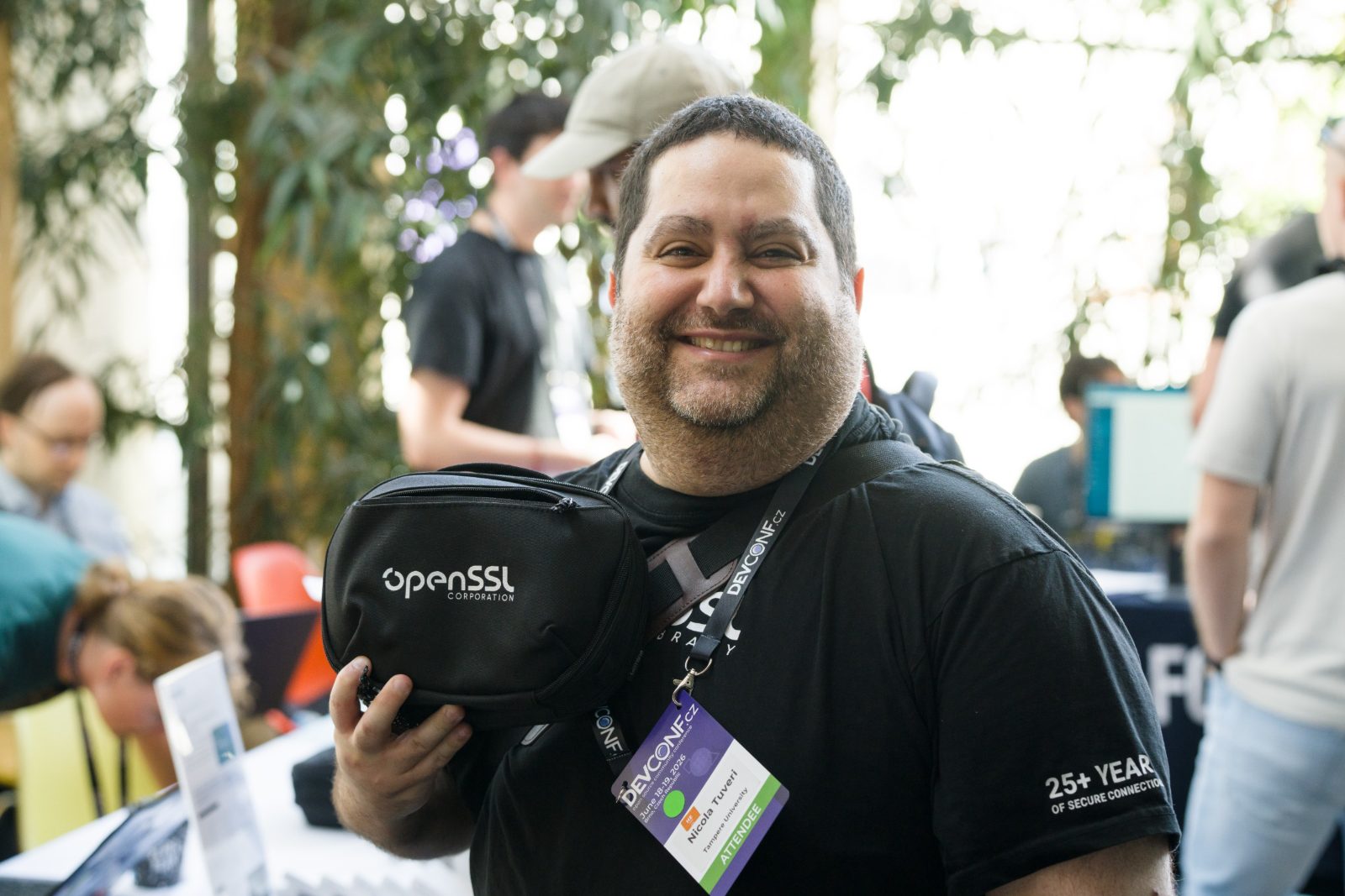 An attendee smiling and holding an OpenSSL Corporation belt bag