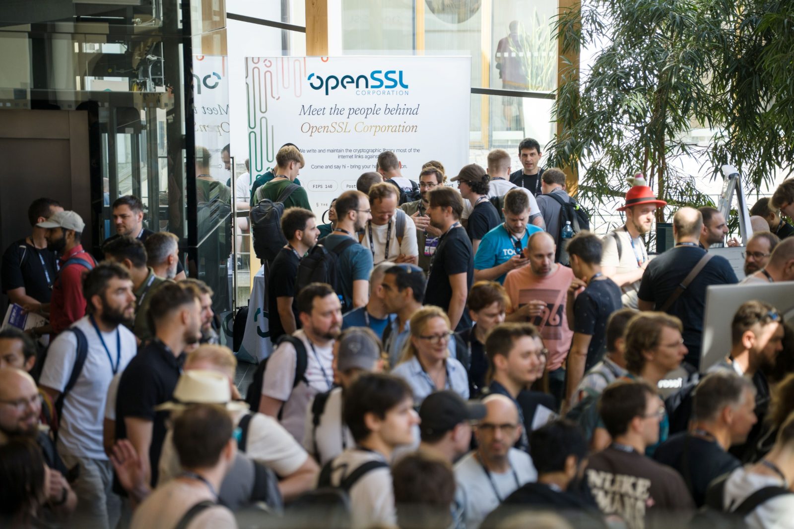 A crowd gathered at the OpenSSL Corporation booth in front of the Meet the people behind OpenSSL Corporation banner