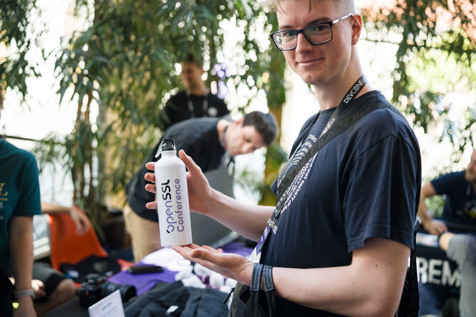 An attendee holding an OpenSSL Conference water bottle at the booth