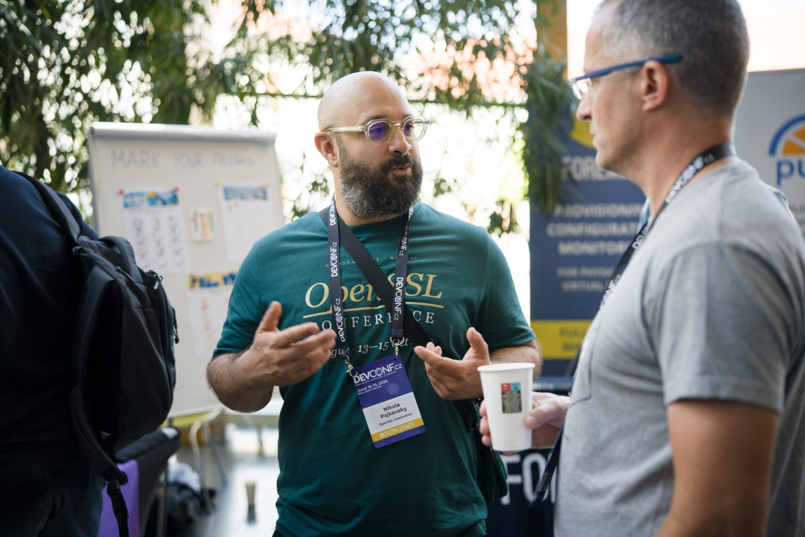 Nikola Pajkovsky in conversation with an attendee, coffee in hand