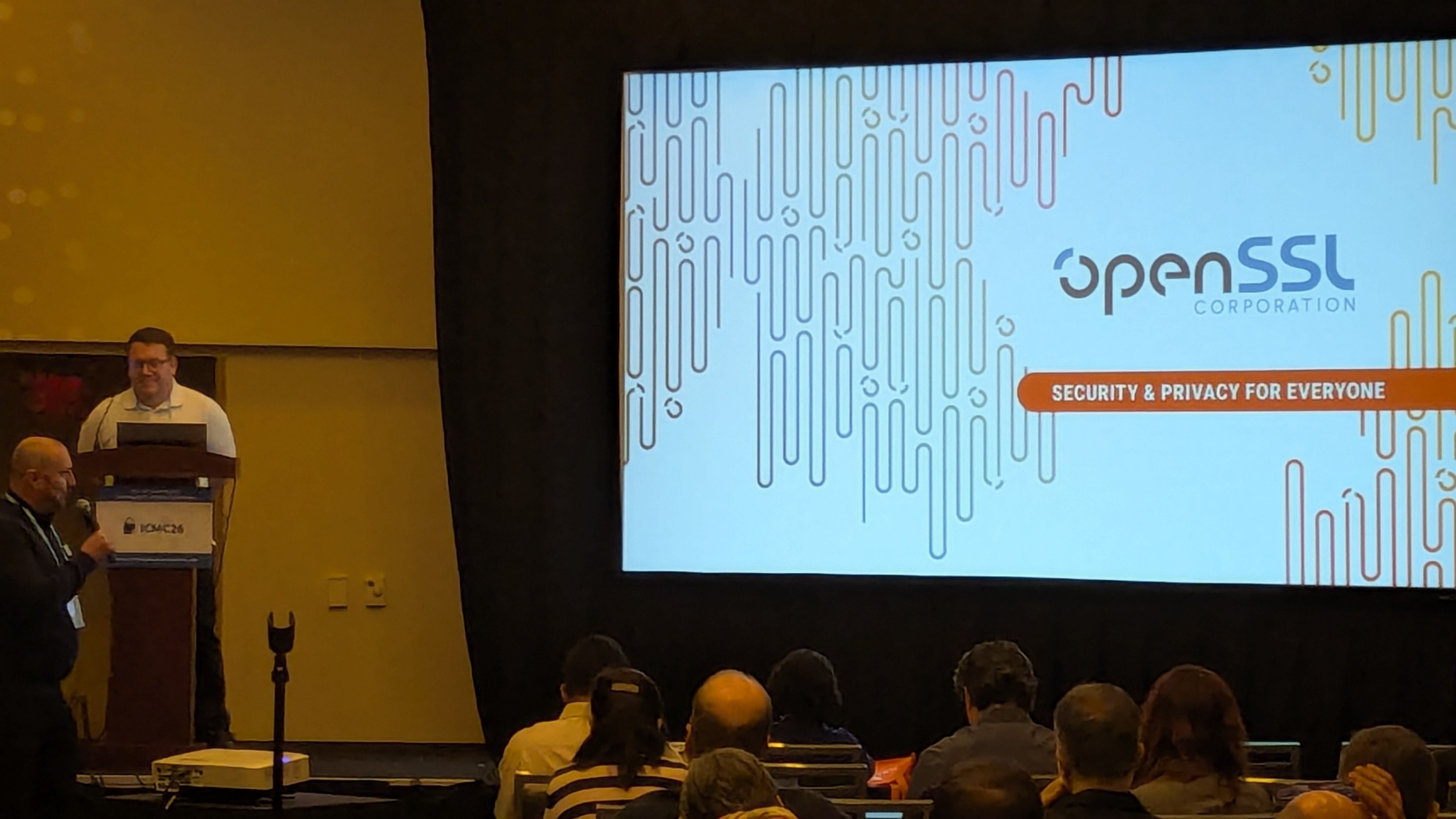 Tomáš Vávra at the podium in Salon 1 with the OpenSSL 3.5 feature slide projected behind him.
